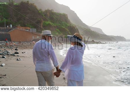 Lifestyle With Caucasian Senior Couple Resting On Beach, Holding Hands, Happy In Love Romantic And R