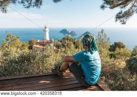 The Tourist Seating, Reaching The Path To The Lighthouse. View Of The Lighthouse Helidonia From The 