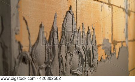 A Worker Plasters The Wall With A Spatula And Applies A Cement Mix Solution. The Repairman Lays The 