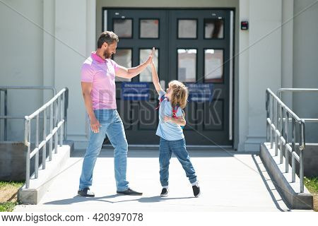 Father Walking Son To School. Parent And Pupil Of Primary School Schoolboy With Backpack.