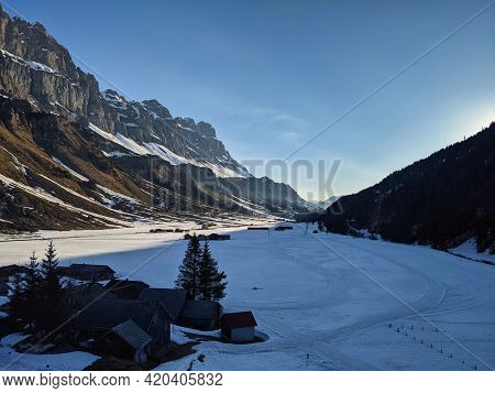 Urnerboden. Cross-country Ski Run And Pass Road In The Picture With High Mountains On The Sides. Uri