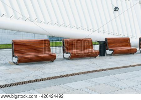 Recreation Area With Empty Contemporary Wooden Benches Along White Curved Wall Near Modern Business 