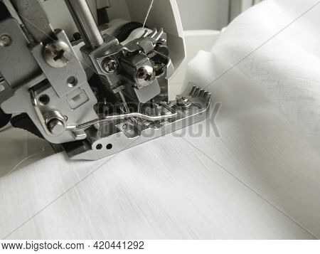 The Overlock Sewing Machine Sews White Fabric. Garment Industry