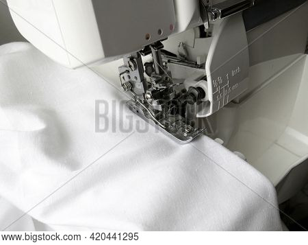 The Overlock Sewing Machine Sews White Fabric. Garment Industry