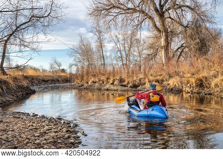 senior male  is paddling an inflatable packraft on a river in early spring spring - Poudre River in northern Colorado