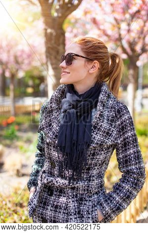 Young Redhed Caucasian Woman Enjoying Spingtime Sakura In Park