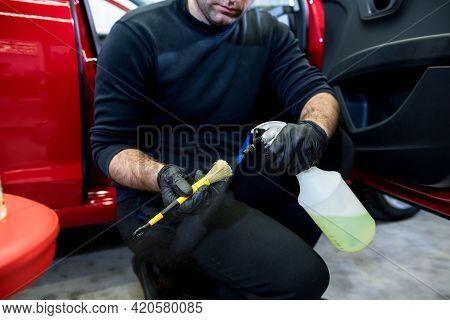 Car Service Worker Cleans Interiror With Special Brush