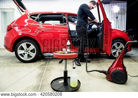 Car Service Worker Cleans Interiror With Steam Cleaner
