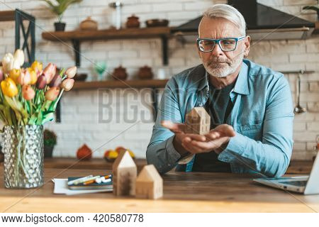 Preservation And Restoration Of Real Estate. A Mature Man Holds A Model Of A House In His Hands. Ref