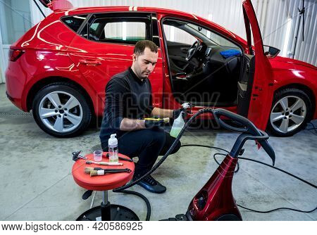 Car Service Worker Cleans Interiror With Special Brush