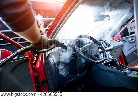 Car Service Worker Cleans Interiror With Steam Cleaner