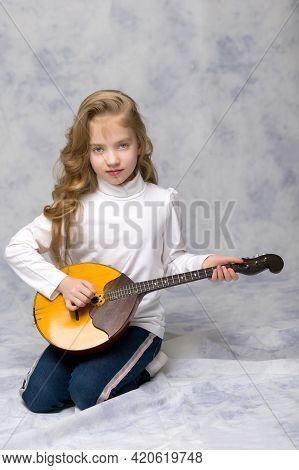 Cute Little Girl Learning To Play The Plucked Musical Instrument, Domra.