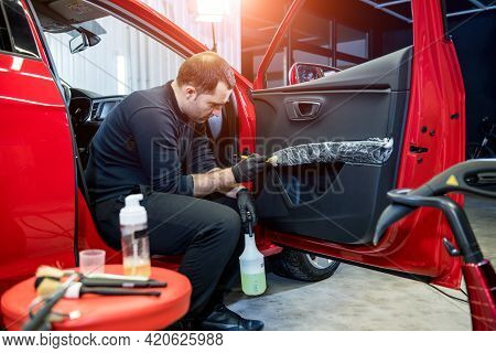 Car Service Worker Cleans Interiror With Special Brush