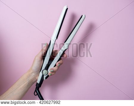 White Curling Iron In A Woman's Hand On A Pnk Background. An Accessory For Creating Hairstyles. Beau