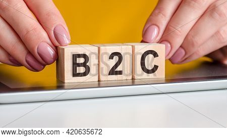 Women Hands Puts A Wooden Blocks With The Letters B2c On The Black Surface Of The Notepad. B2c Short