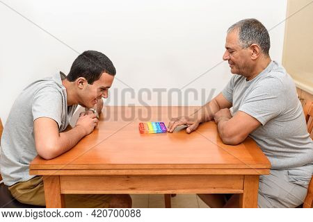 Teenager Son And Senior Father Playing With The Pop It Fidget. Poppit New Fidget Toy, Popular With K