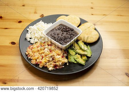 Typical Venezuelan Breakfast Scrambled Eggs With Tomato Called Perico, Black Beans, Hard White Chees