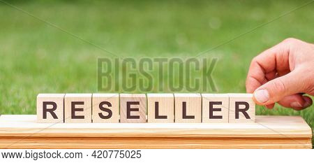 Reseller Is A Word Written On Wooden Blocks. A Man's Hand Holds A Wooden Cube With The Letter R From