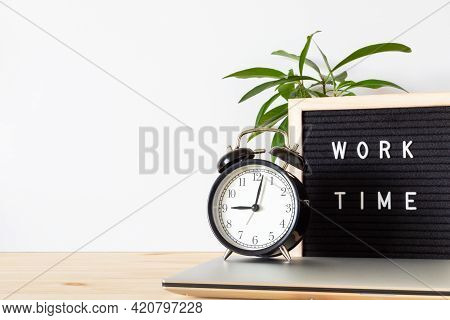 Classic Black Alarm Clock, Laptop And Black Board With Words 'work Time' On Wooden Table With White