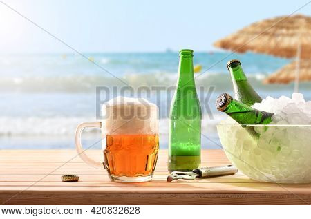 Beer Mug And A Glass Container With Ice Filled With Beer Bottles On Wooden Base And Beach Background