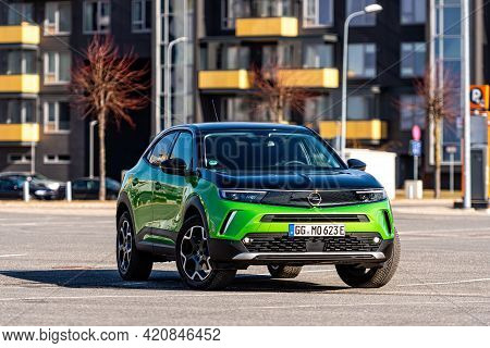 Riga, Latvia - 26 March, 2021: Green Electric Vehicle Opel Mokka-e In The Parking Lot On The Backgro