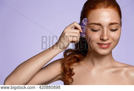 Beauty Ginger Girl Self Massage Facial Skin With Natural Jade Quarz Gua Sha Scraper. Woman Uses Faci
