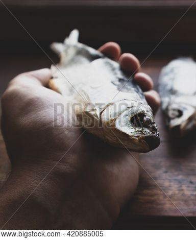 Dried Fish In Hand On Blurred Background