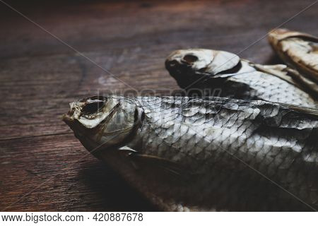 3 Dried Fish On A Wood Background In The Process Of Drying