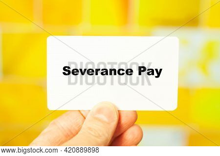 Severance Pay. Financial Text In Male Hand On Yellow Background At Home