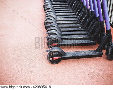 Russia, Sochi 16.04.2021. Many Electric Scooters Are Lined Up On A Pink Road Surface.