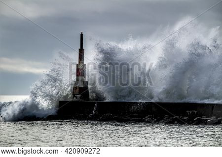 Giant Waves Breaking On The Breakwater And The Lighthouse On Aguda Beach, Miramar, Arcozelos Town