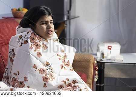 An Indian Woman In Fever Sittiing On Sofa