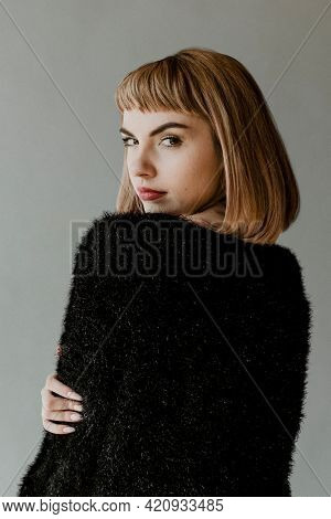 Brown hair woman in a black fluffy sweater looking back over her shoulder