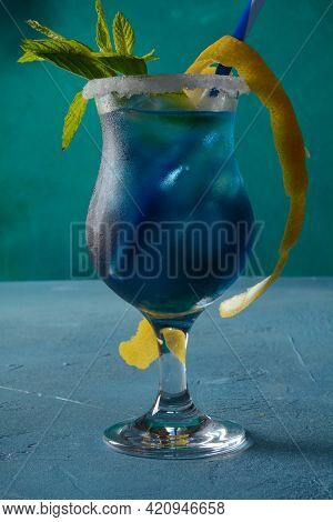 Blue Lagoon Cocktail With Blue Curacao Liqueur, Vodka, Lemon Juice And Soda, Decorated With Lemon Sl