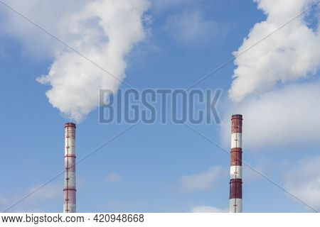 Two Pipes And Smoke From Them Against The Blue Sky. Industrial Landscape. Front And Bottom View.