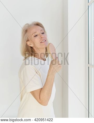 Happy Carefree Mature Woman With Hairbrush As Mic Singing Her Favourite Song And Having Fun At Home.