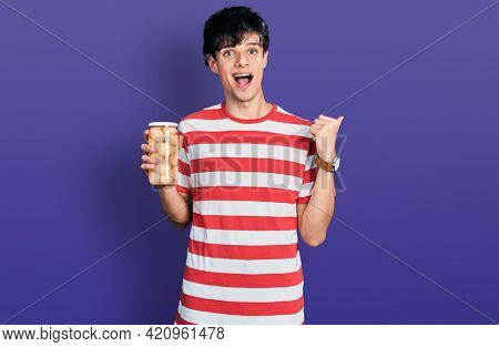 Handsome hipster young man holding bottle with boiled potatoes pointing thumb up to the side smiling happy with open mouth 