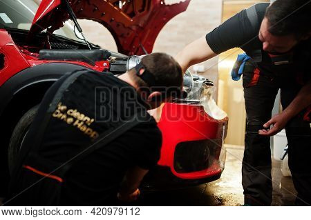 Car Service Worker Put Anti Gravel Film On A Red Car Body At The Detailing Vehicle Workshop. Car Pro