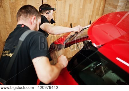 Car Service Worker Put Anti Gravel Film On A Red Car Body At The Detailing Vehicle Workshop. Car Pro