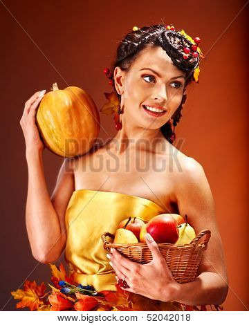 Woman holding autumn basket with fruit and vegetable.