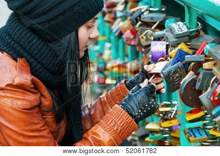 Girl opening a lock on a bridge