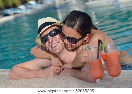 happy young couple relax and take fresh drink at summer vacation on swimmin pool
