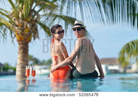 happy young couple relax and take fresh drink at summer vacation on swimmin pool