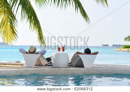 happy young couple relax and take fresh drink at summer vacation on swimmin pool
