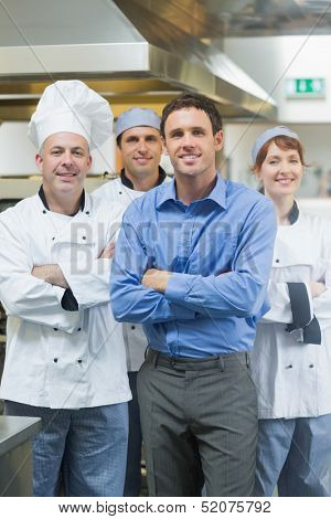 Handsome manager posing with some chefs in a kitchen