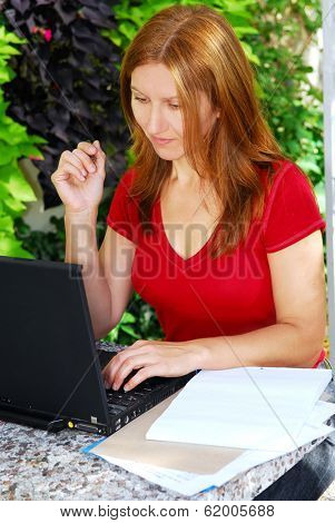 Happy mature woman working on a portable computer in her garden