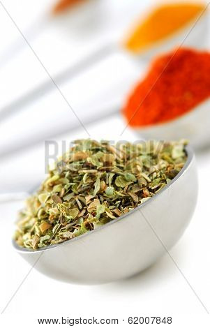 Assorted spices in metal measuring spoons on white background