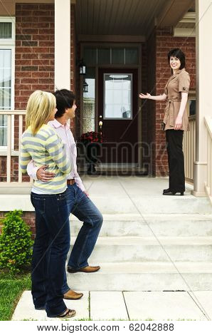 Real estate agent with couple welcoming to new home
