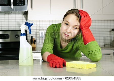 Tired girl doing kitchen cleaning chores with rubber gloves