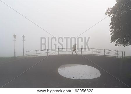 Lone Hiker On Sad Morning Walk Over A Bridge